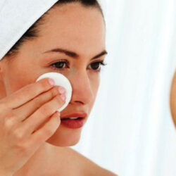 chica mirandose a espejo con algodón para tonificar su cara