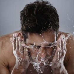 Hombre lavandose la cara para hidratrsela con aceite de argan antes de dormir