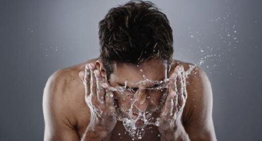 Hombre lavandose la cara para hidratrsela con aceite de argan antes de dormir