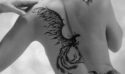 espalda de chica tatutada con ave fenix en blanco y negro y fondo gris