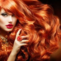 Chica de largo pelo pelirrojo con anillo en forma de flor y fondo oscuro